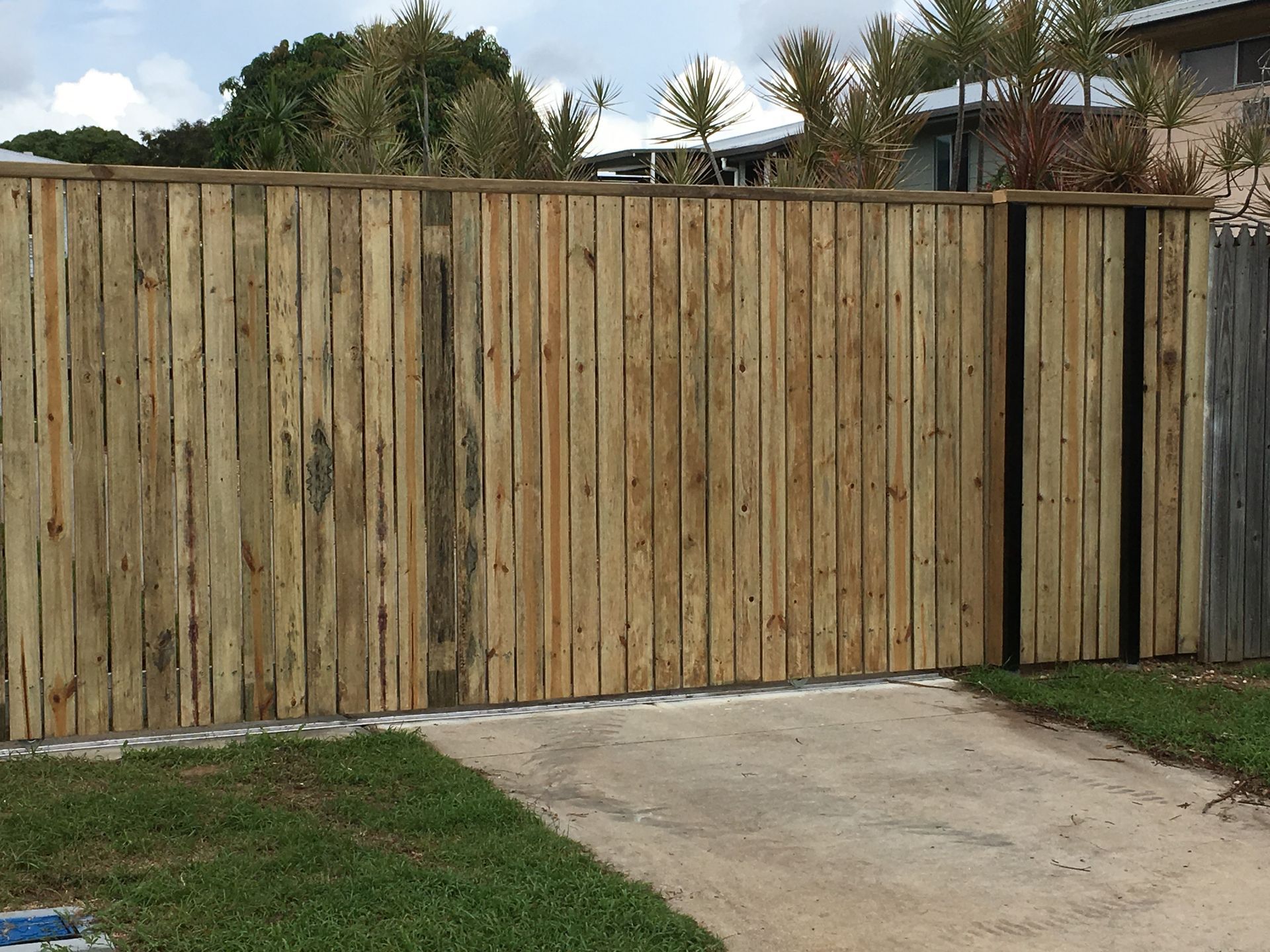Wooden Privacy Fence Beside a Concrete Driveway and Patchy Grass in a Suburban Yard — Fencing Around in Garbutt, QLD