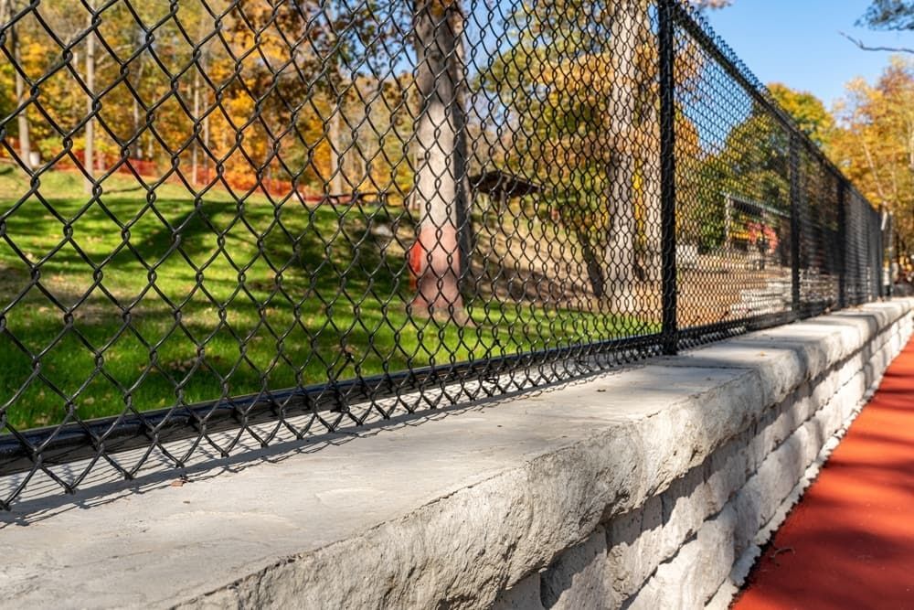 Chain-link Fence Beside a Red Path and Concrete Wall in a Sunny Park — Fencing Around in Garbutt, QLD
