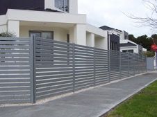 Modern House With a Long Gray Metal Fence Along a Sidewalk and Driveway — Fencing Around in Garbutt, QLD