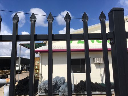 Black Metal Fence in Front of a Small White Building Under a Blue Sky With Clouds — Fencing Around in Garbutt, QLD