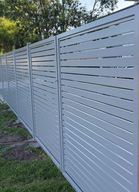 White Horizontal-slat Metal Fence Along a Grassy Yard Edge — Fencing Around in Garbutt, QLD