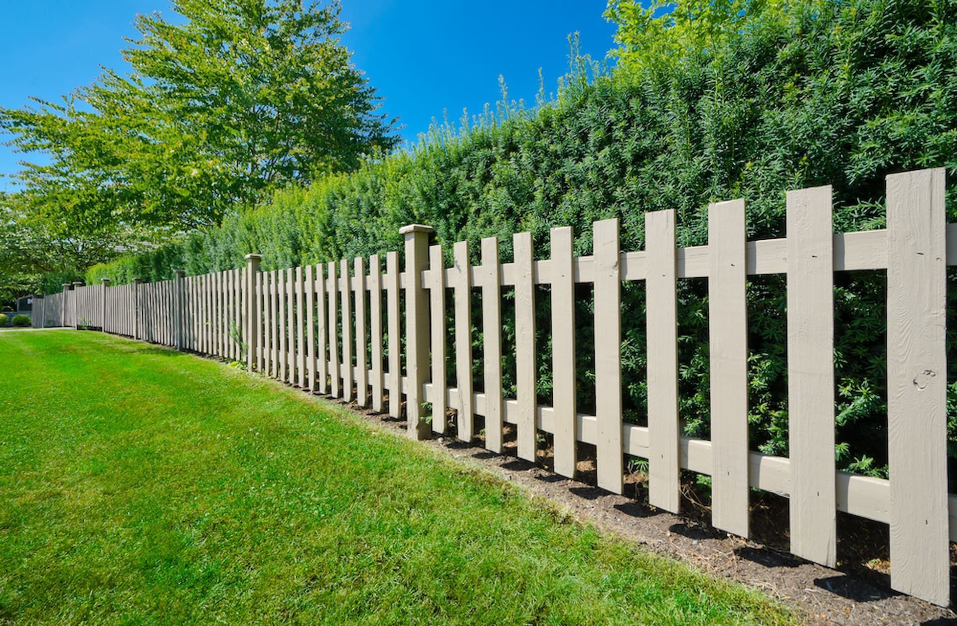 Light Brown Wooden Picket Fence Along Green Lawn And Lush Hedge In Townsville