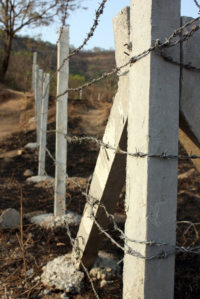 Barbed Wire Fence With Concrete Posts Along a Dry Hillside Under Bright Sunlight — Fencing Around in Garbutt, QLD