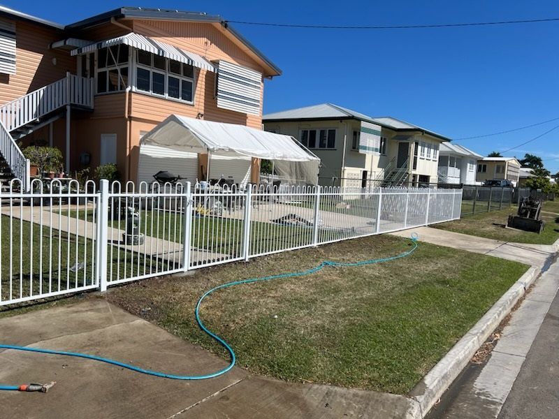 Suburban Houses Behind a White Fence With a Blue Hose on the Lawn by the Curb — Fencing Around in Garbutt, QLD