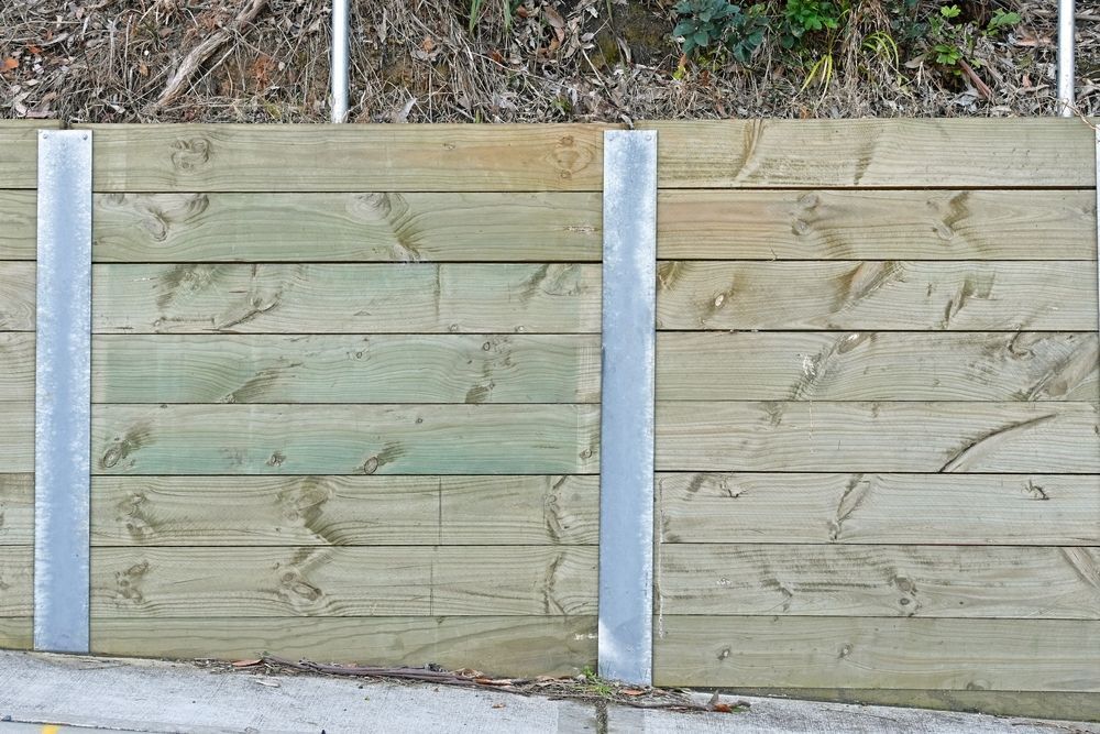 Wooden Retaining Wall With Concrete Posts Beside a Paved Path — Fencing Around in Garbutt, QLD