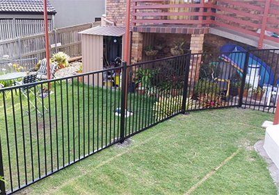Backyard With Black Metal Fence, Grassy Lawn, Flowerbeds — Fencing Around in Garbutt, QLD