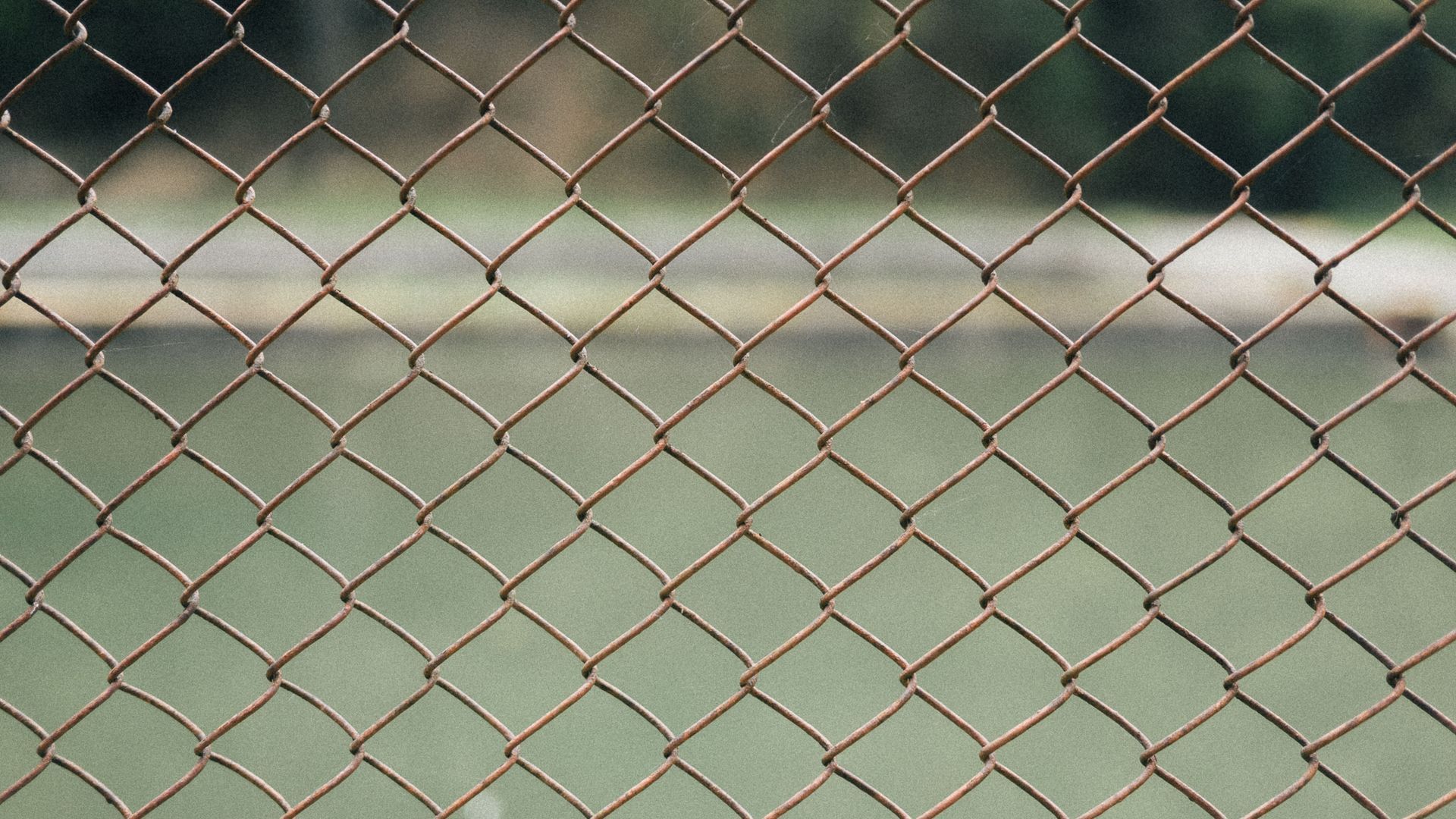 Chain-link Fence in Front of a Blurred Green Sports Field and White Boundary Line — Fencing Around in Garbutt, QLD