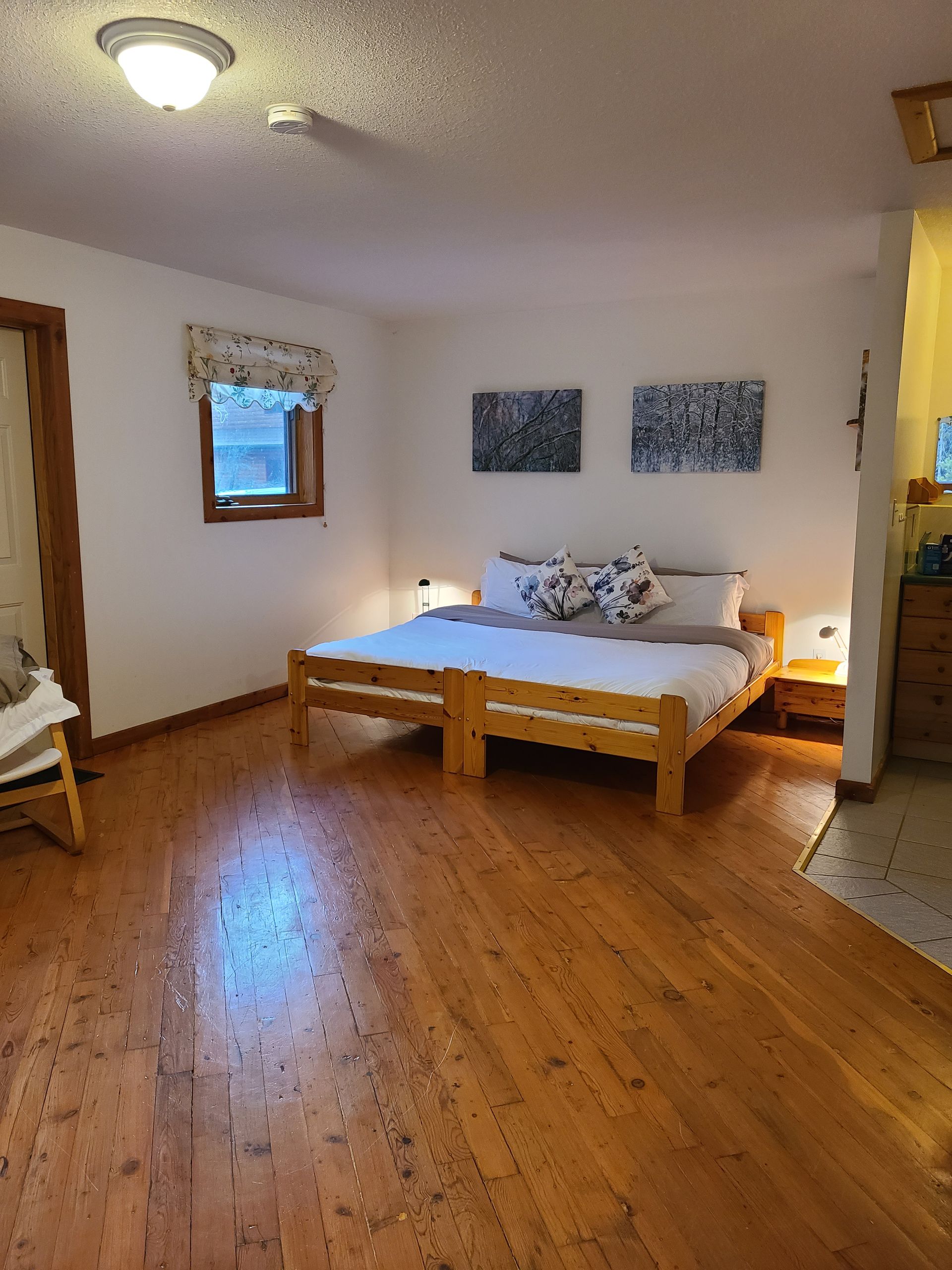 Bedroom with a double bed, wooden floor, and artwork on the wall.