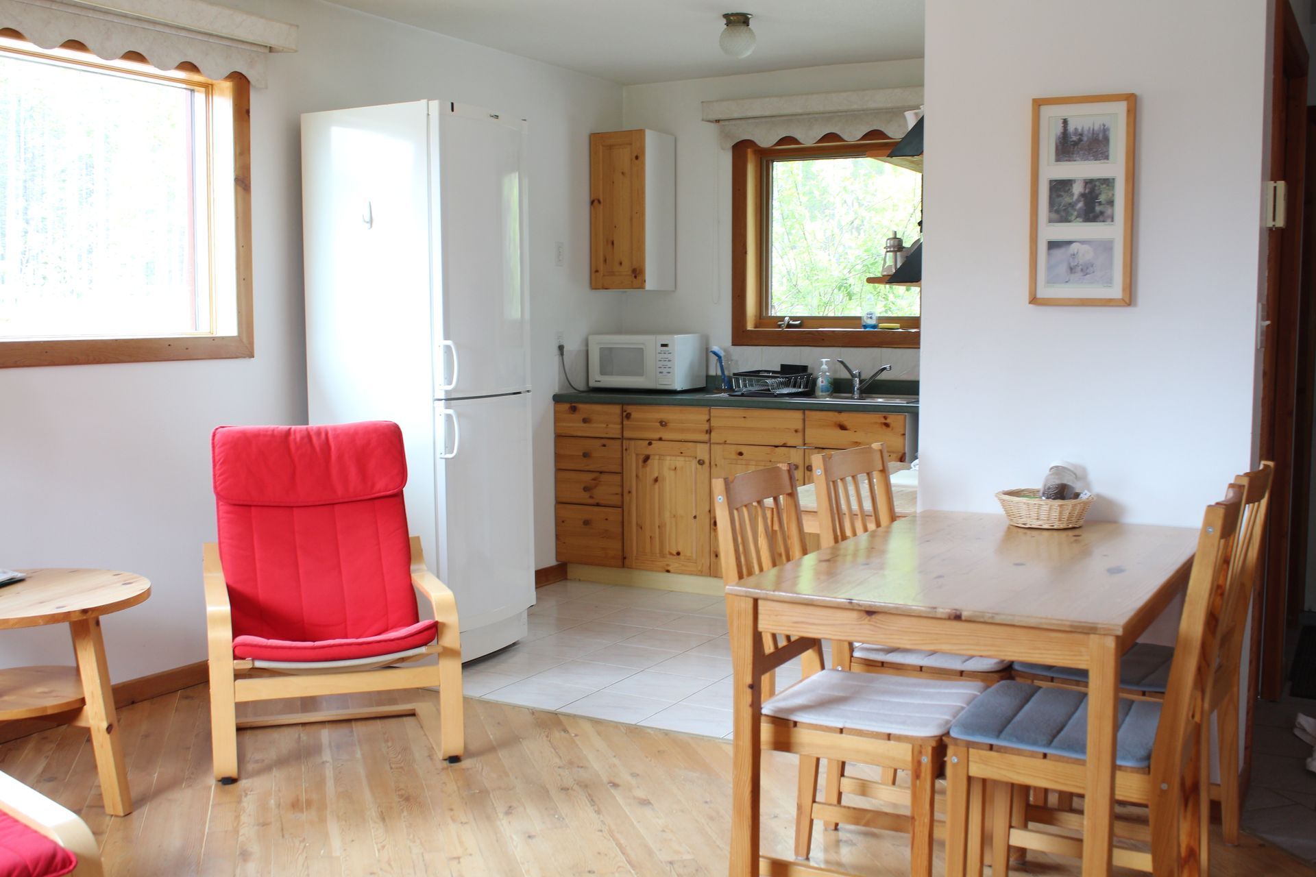 Cozy kitchen and dining area with red chair, wooden table and chairs, and a window.
