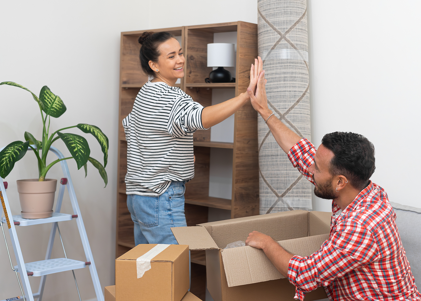 A man and a woman are giving each other a high five in a living room.
