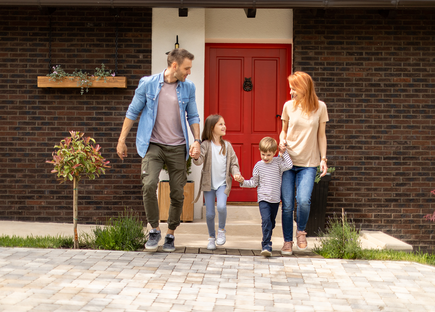 A family is walking out of their house holding hands.