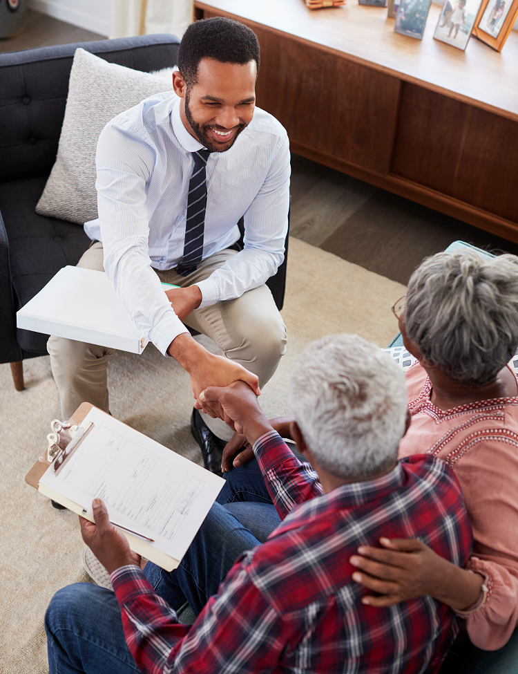 A man is shaking hands with an older couple while sitting on a couch.