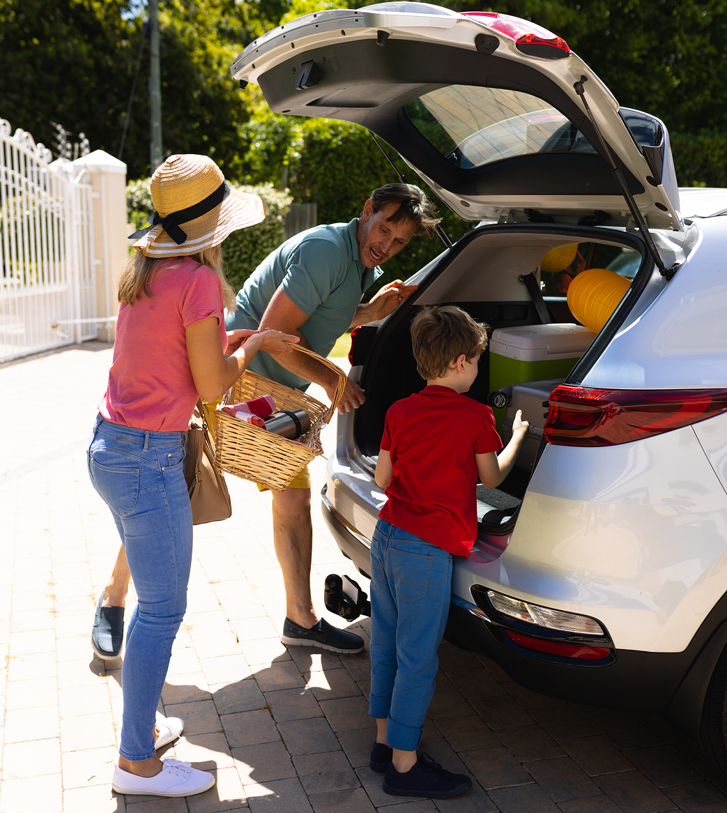 A family is putting something in the back of a car.