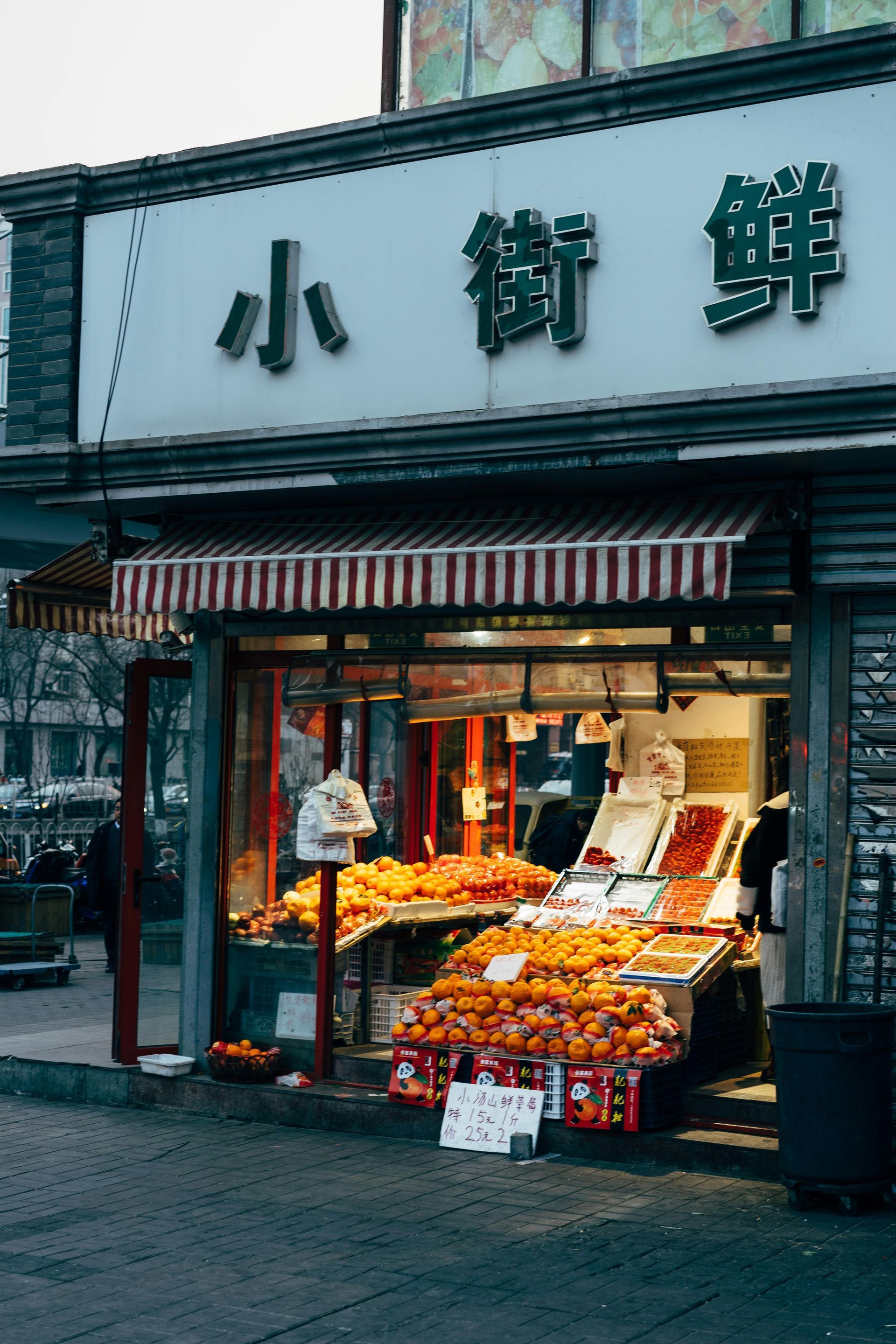 A fruit stand in front of a building with chinese writing on it.