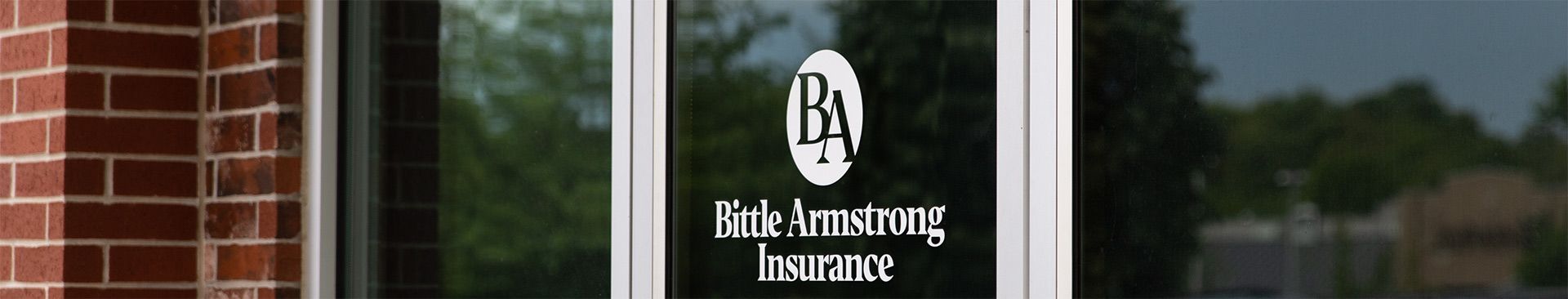 The Bird Armstrong Insurance logo on a glass office door next to a brick wall.