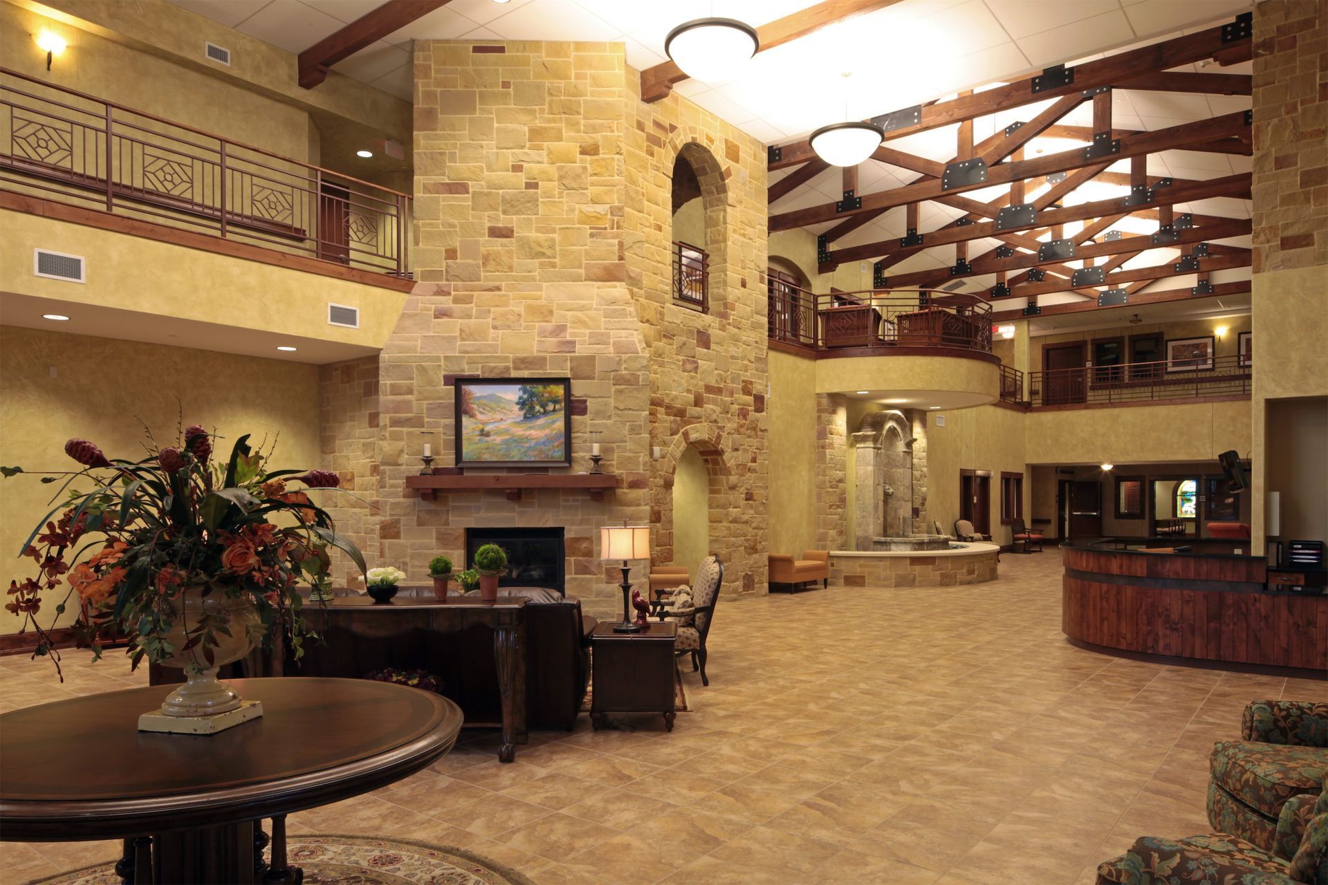 Spacious hotel lobby with stone fireplace, warm lighting, lounge seating, and a front desk counter