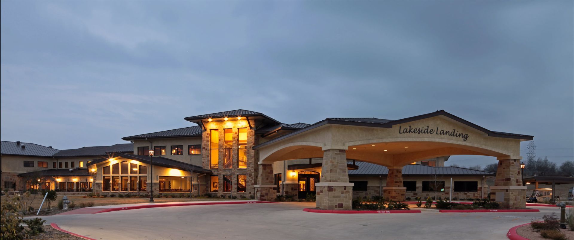 Modern building entrance at dusk with warm lights and large arched canopies