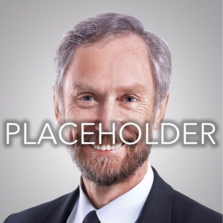 A man in a suit and tie is smiling in front of the word placeholder