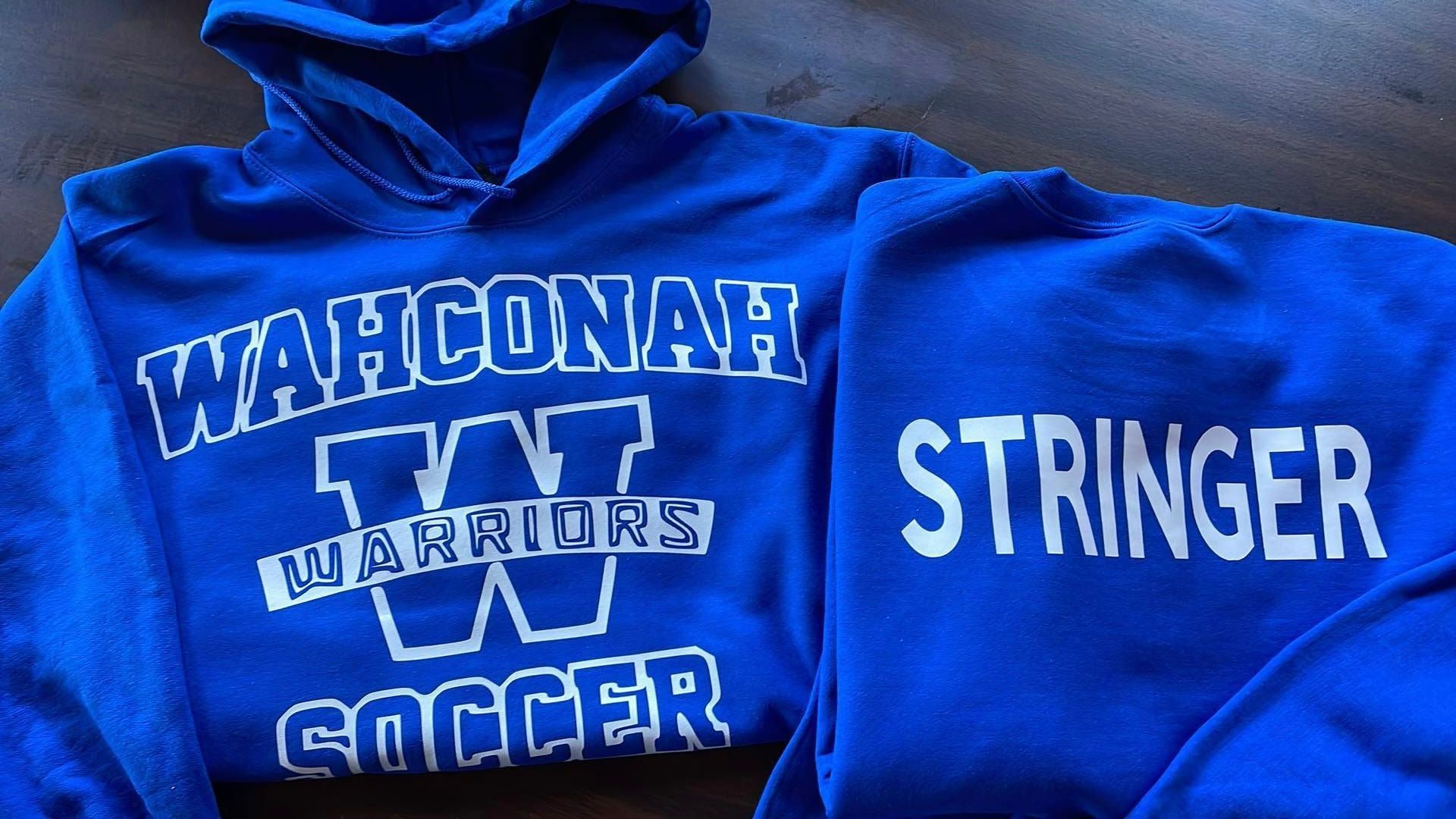 Two blue Wahconah Warriors soccer sweatshirts, one showing the team logo and the other with the name 
