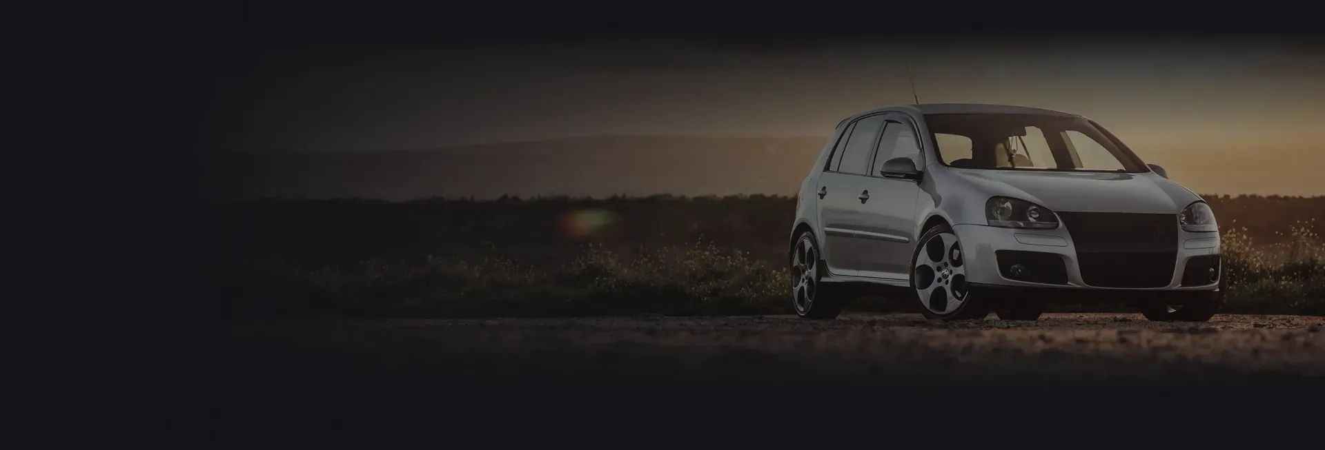 Silver car parked outside with sunset in background | Auto Brakes & Lube