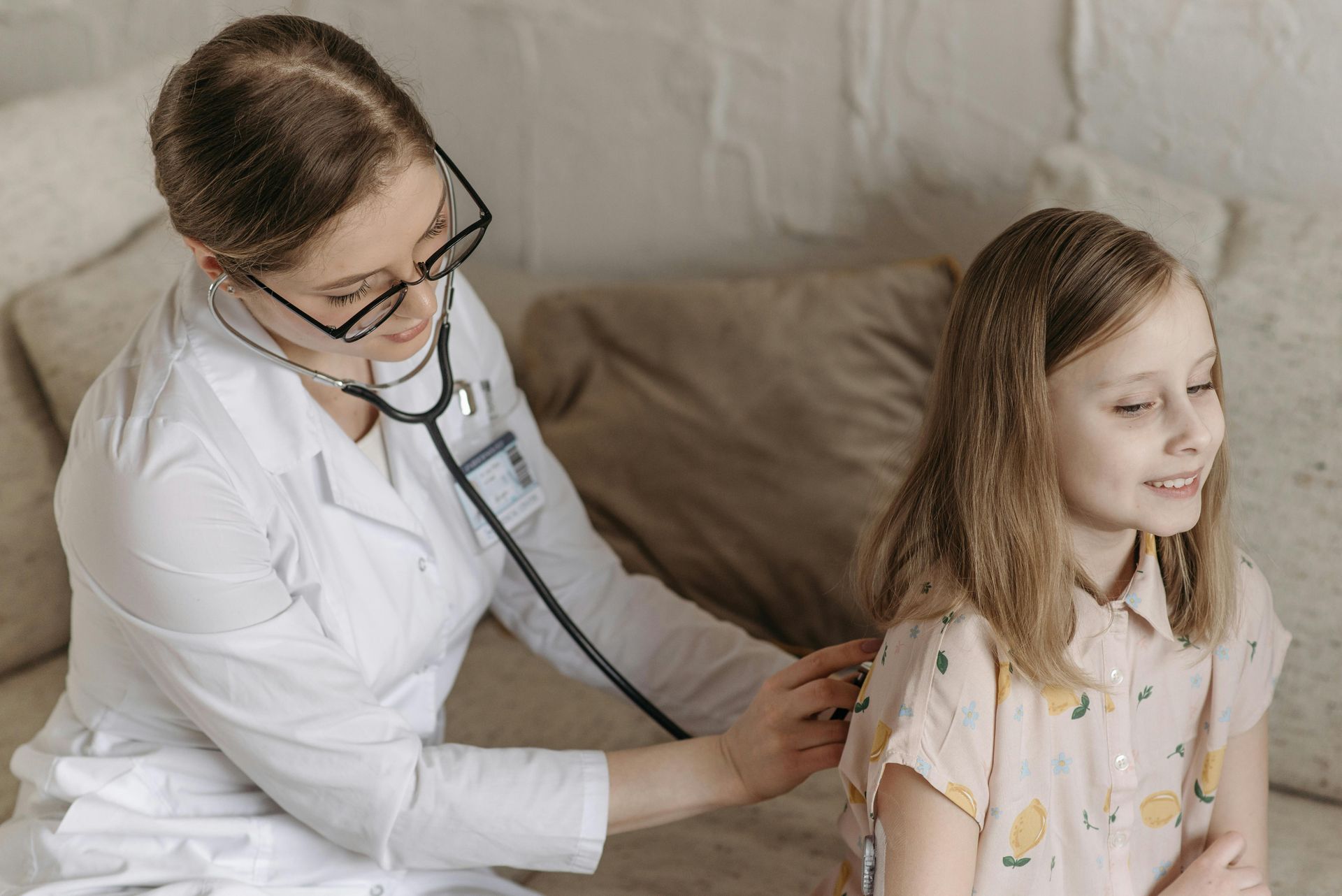 A doctor is examining a young girl with a stethoscope.