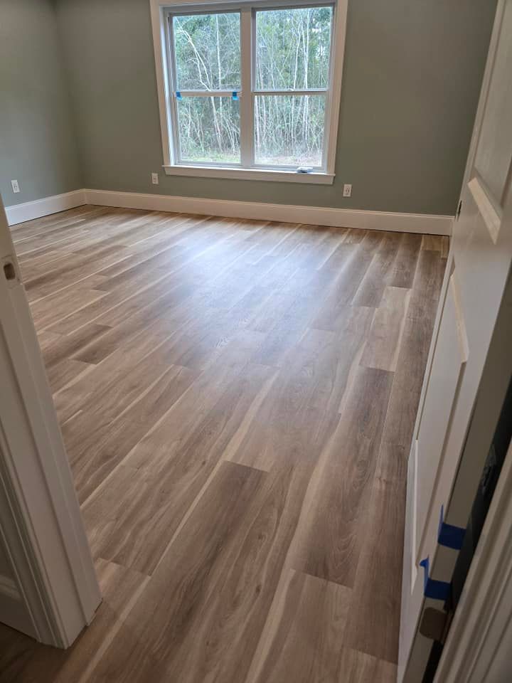 A bedroom with hardwood floors and a window.