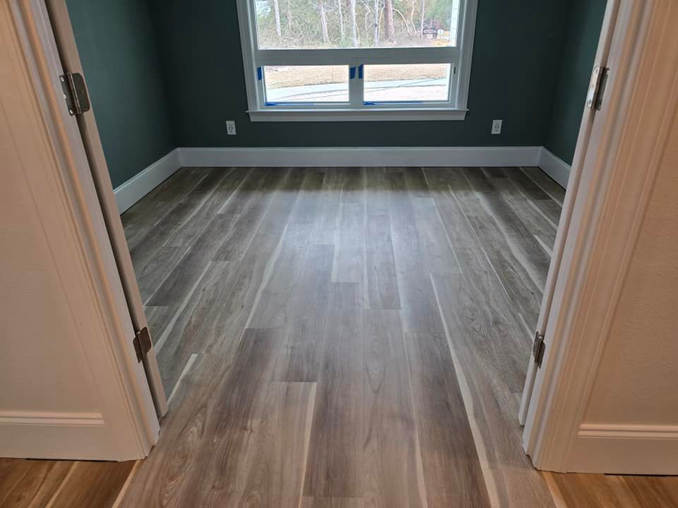 A bedroom with hardwood floors and a window.