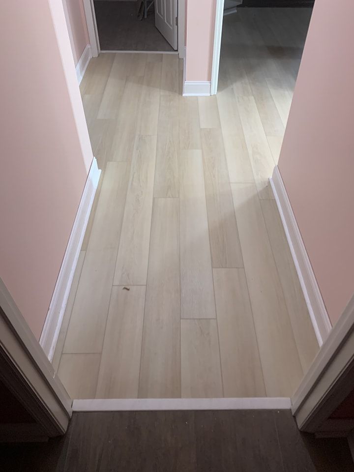 A hallway with hardwood floors and pink walls.