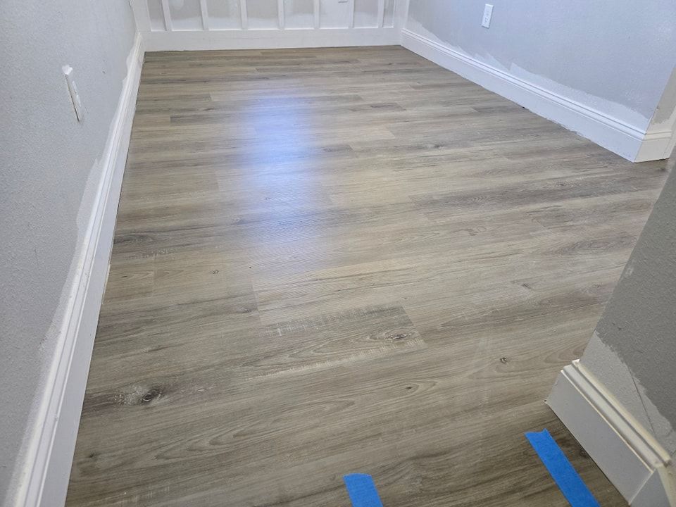 A room with a wooden floor and a blue tape on the floor.