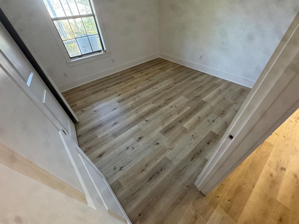 A bedroom with hardwood floors and a window.