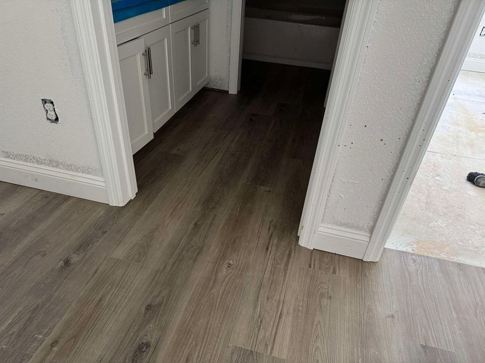 A bathroom with hardwood floors and white cabinets.