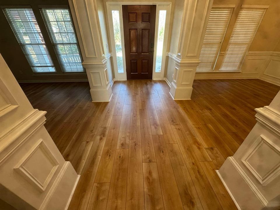 A hallway with hardwood floors and a wooden door.