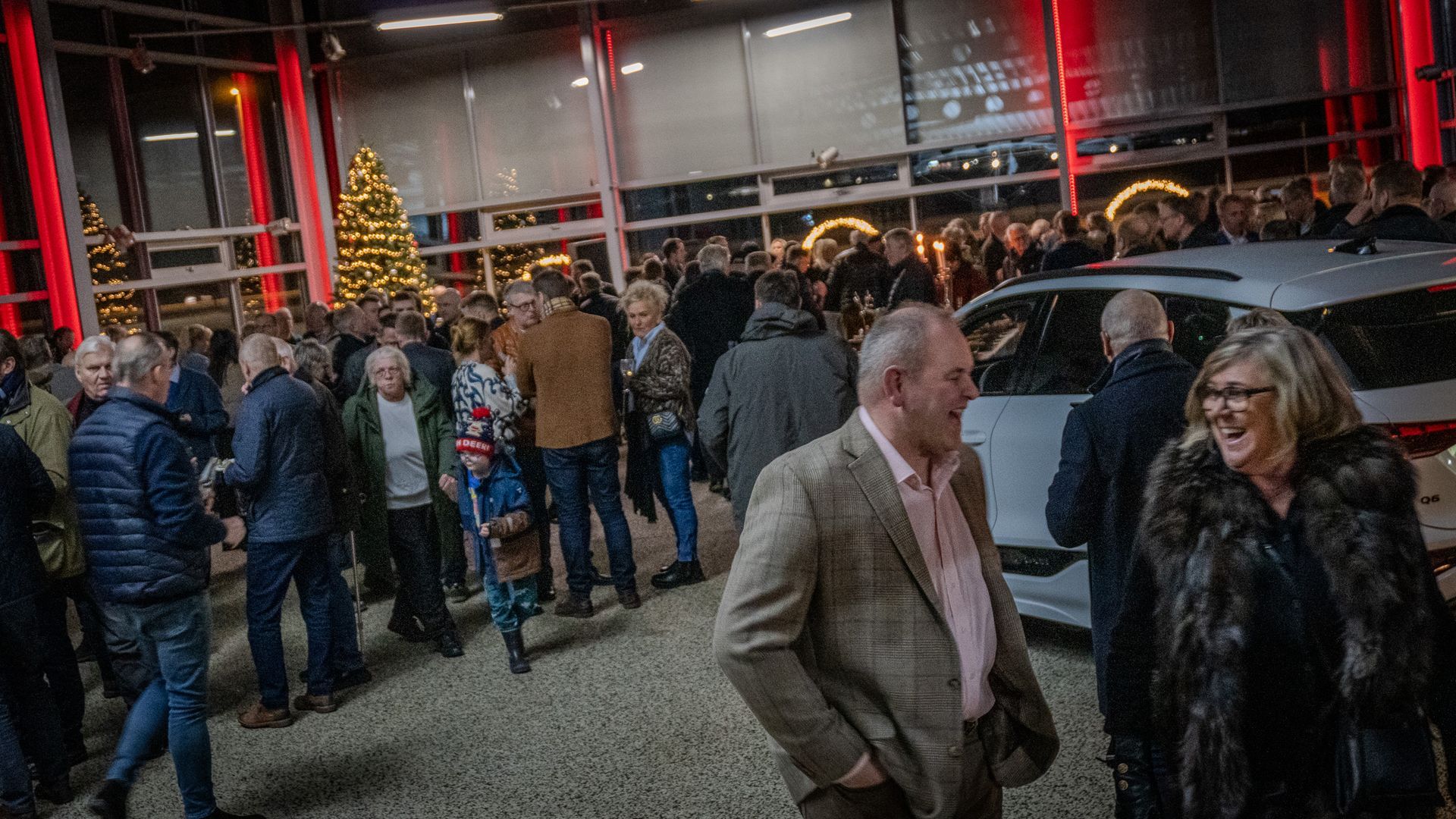 A group of people are standing around a car dealership.