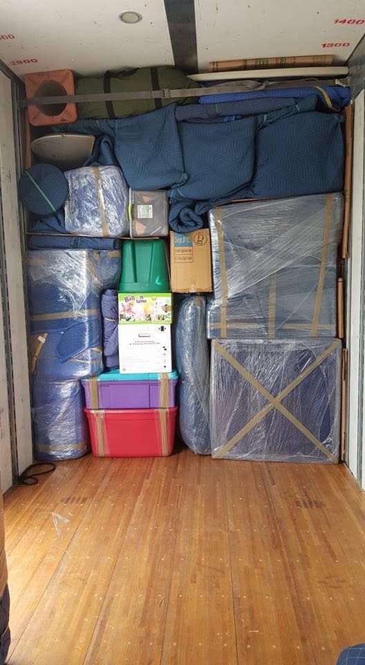 Boxes, furniture wrapped in blue pads, and household items loaded in a moving truck.