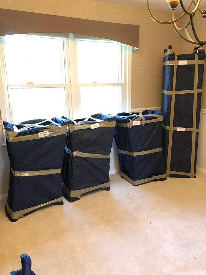 Moving blankets stacked and taped together, ready for transport, positioned in a room with a window.