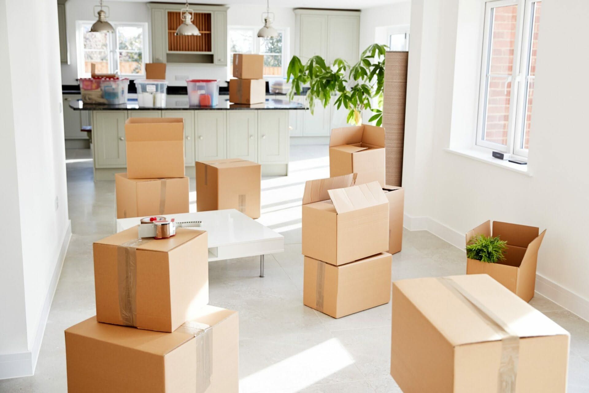 Family unpacking boxes in a new home, a toddler looking at a paper with parents, surrounded by packed boxes.