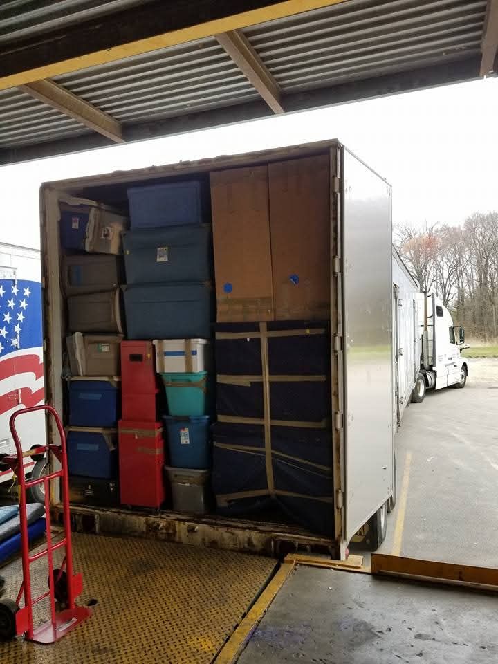 Truck trailer loaded with various storage bins and boxes. Docked at a loading area.