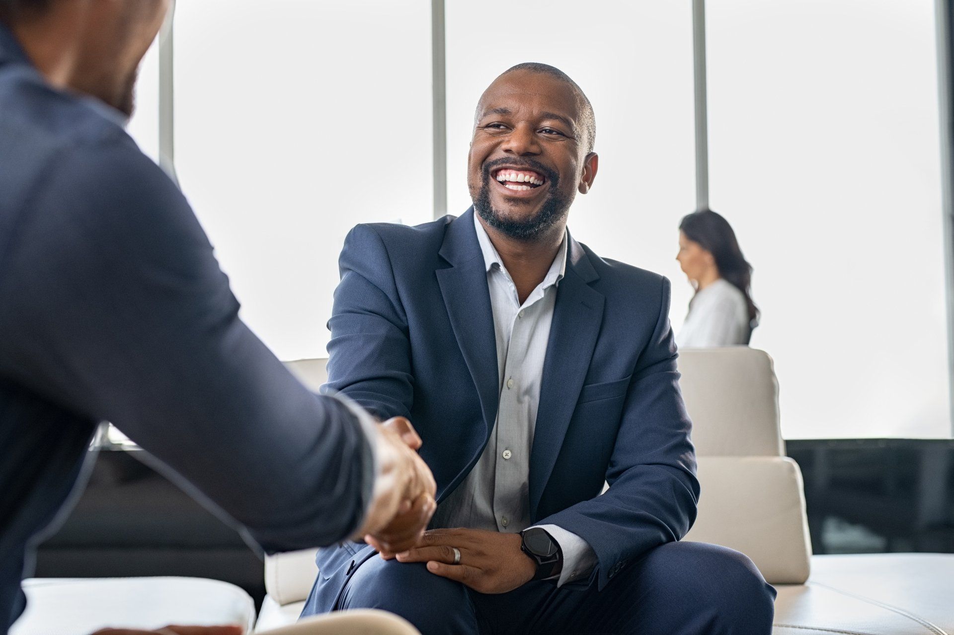 Prepare your managers to have engaging conversations about compensation. Two employees shaking hands engaged in a positive conversation.