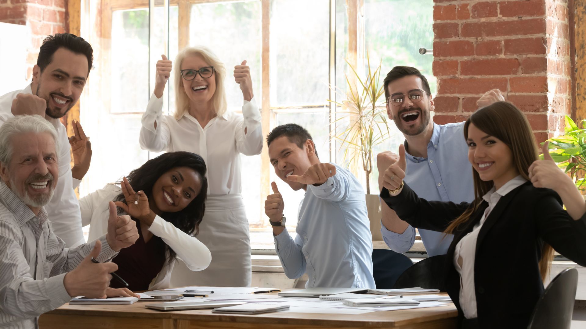 Winning teams start with a strong HR strategy and courageous culture. Seven energized and positive employees in meeting.