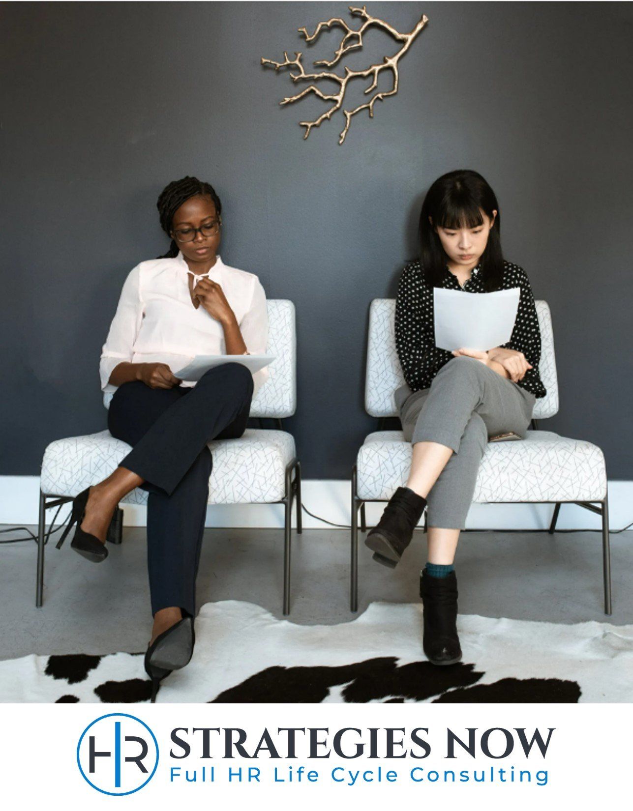 A winning team starts with efficient and effective hiring practices - Right people, right seats. Two employees sitting in lobby reviewing documents.