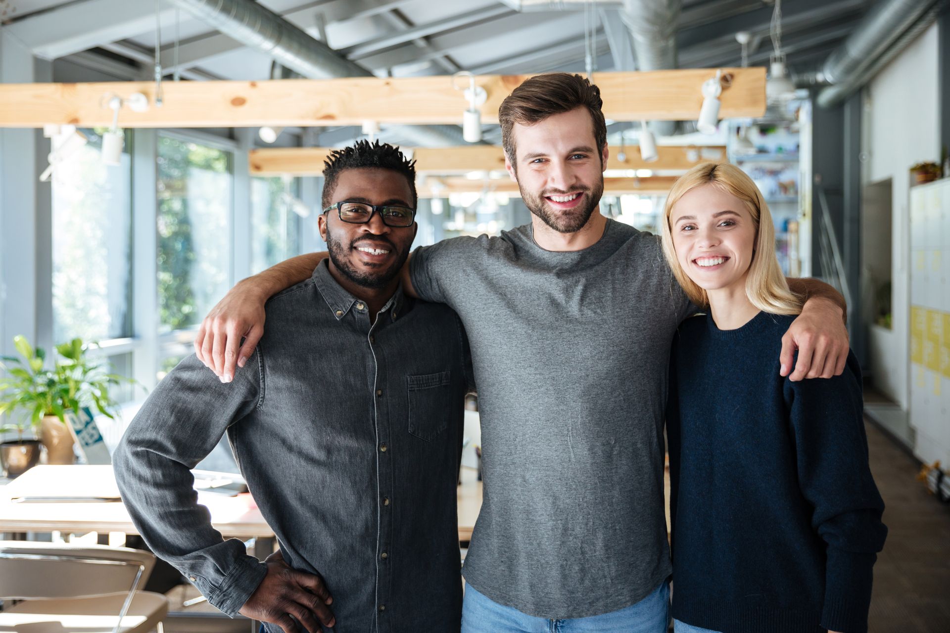 Courageous cultures build team unity and cohesion. Three employees standing together with confidence.