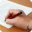a person is writing on a piece of paper with a pen .