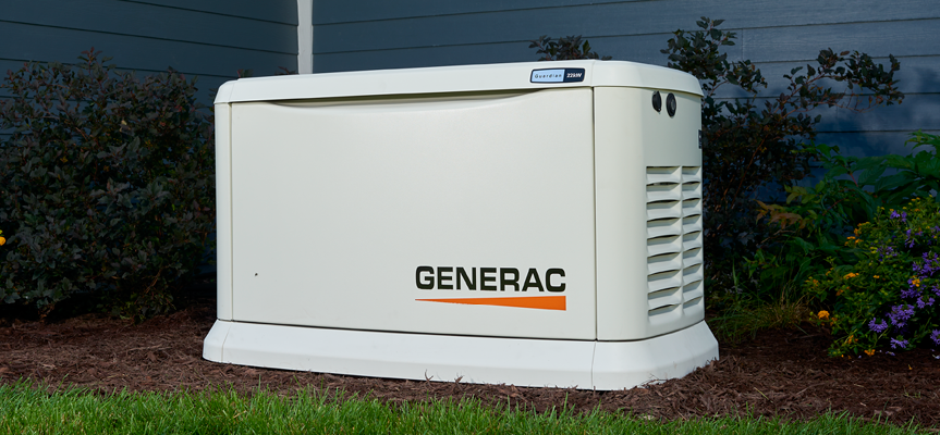 A generac generator is sitting in the grass in front of a house.