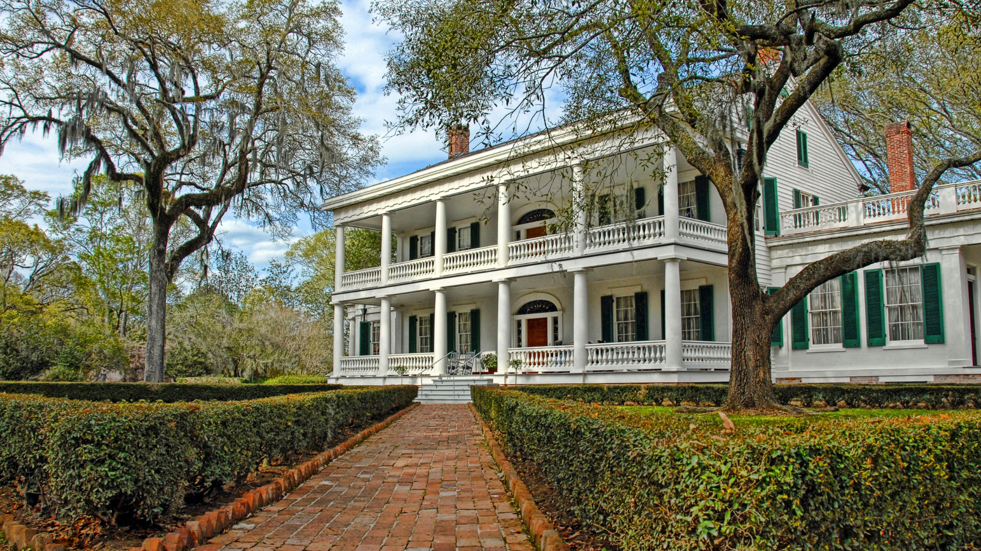 A large white house with a brick walkway leading to it.