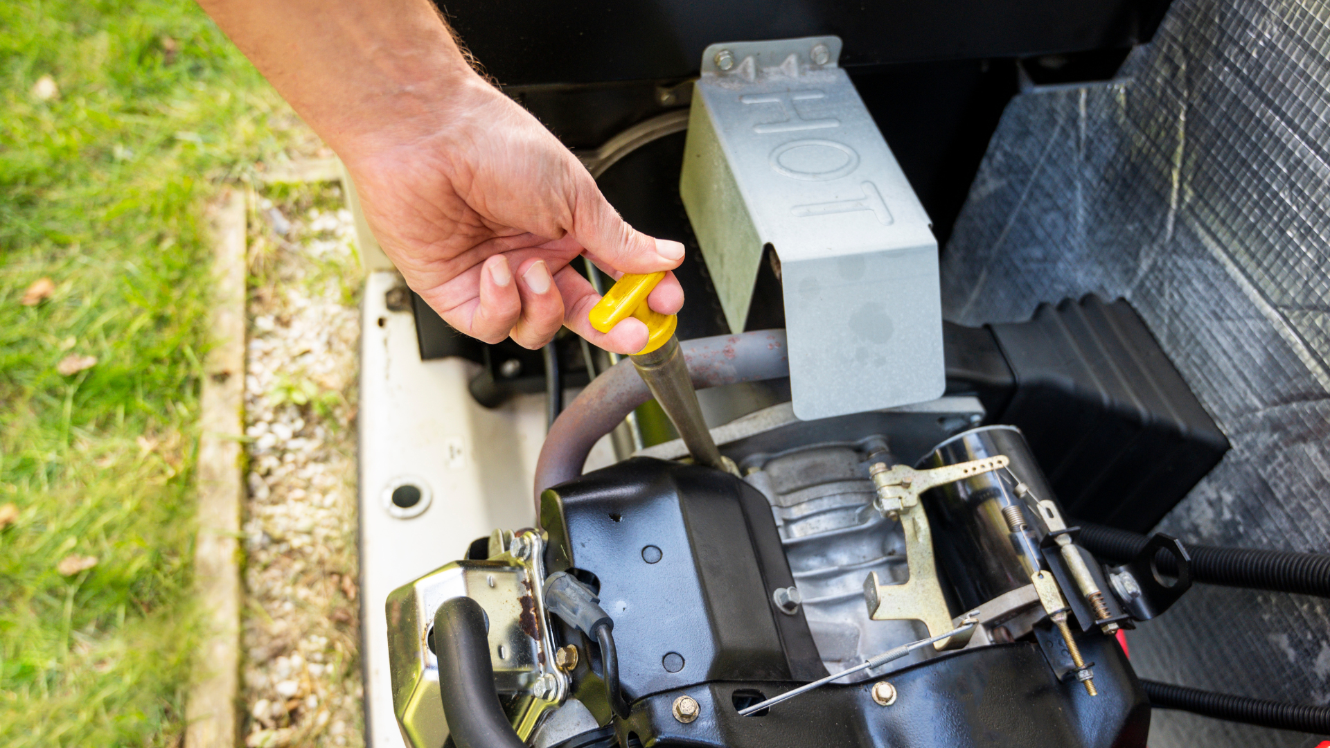 A person is checking the oil level of a generator with a screwdriver.