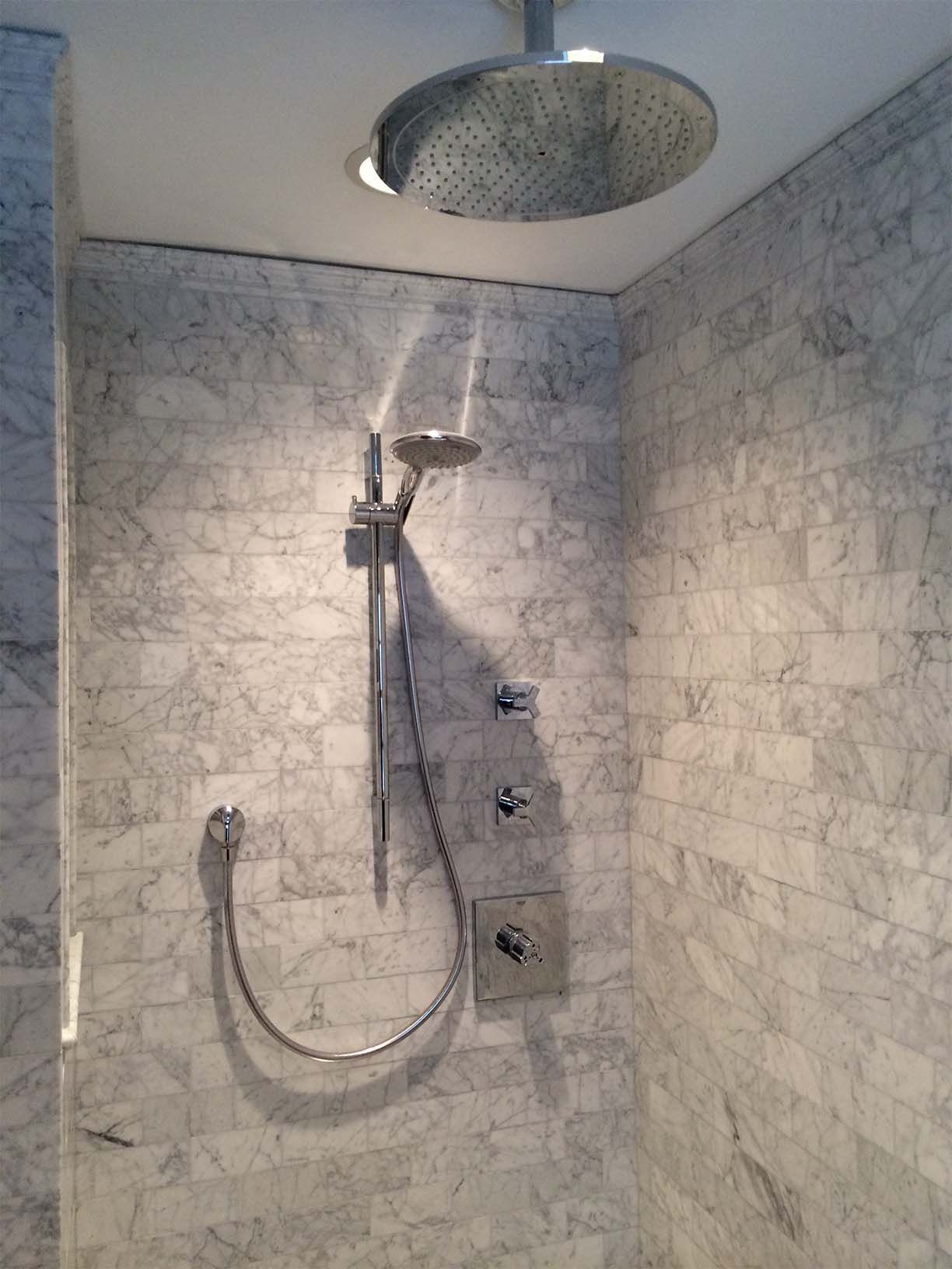 A shower head is hanging from the ceiling in a bathroom.