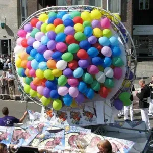 Gigantisch ballonsculptuur in een parade, met talloze kleurrijke ballonnen op een praalwagen.