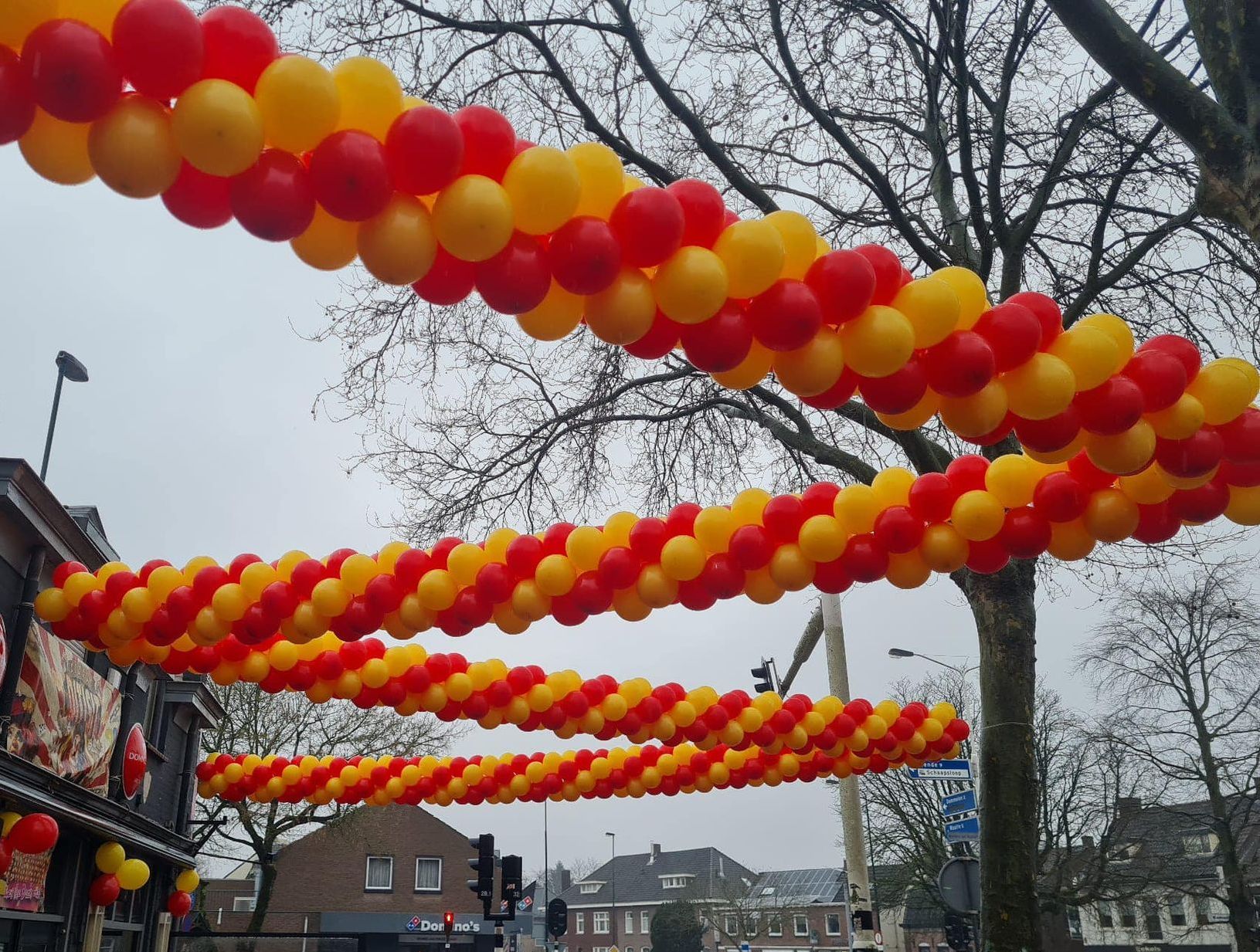 Rijen rode en gele ballonnen hingen over straat en versierden een winkelpui.