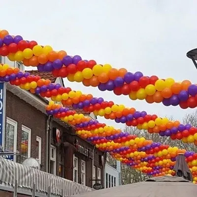 Kleurrijke ballonnenslingers hangen over straat voor de gebouwen.