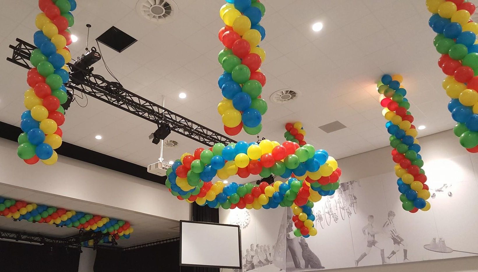 Kleurrijke ballondecoraties kronkelen aan het plafond van een kamer en lijken op zuilen en vormen.